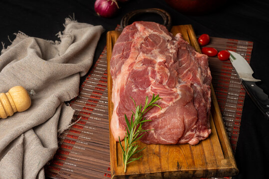 pork in a piece, cut bondiola on a table with vegetables rustic napkin pepper.
