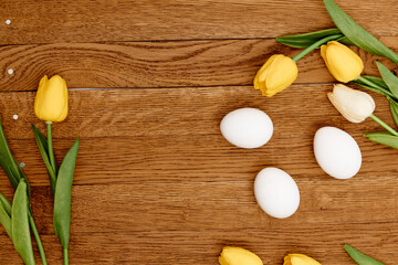 white chicken eggs yellow tulips spring holiday wooden background