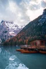 Fototapeta na wymiar Several rowing boats at wooden pier and rental building, Lake Braies, South Tyrol, Italy. Autumn mountain landscape photo.