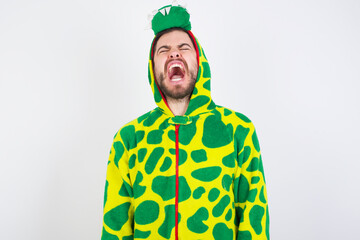 young caucasian man wearing a pajama standing against white background angry and mad screaming frustrated and furious, shouting with anger. Rage and aggressive concept.