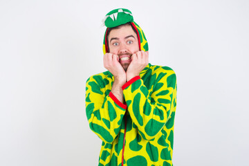 Fototapeta premium Fearful young caucasian man wearing a pajama standing against white background keeps hands near mouth, feels frightened and scared, has a phobia, Shock and frighted concept.