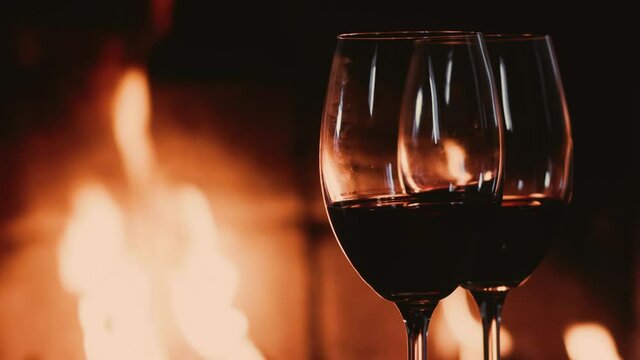Red wine next to a fireplace, cozy and relaxing atmosphere at countryside home, romantic evening and holiday time background, quality drink and luxury rest