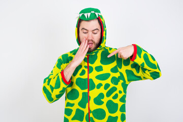 Fototapeta premium Shocked young caucasian man wearing a pajama standing against white background look surprisedly down, indicates at blank with fore finger, Scared model