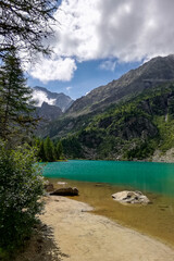 High and sharp rocky peaks of Italian Alps behind colourful water in  Aviolo lake, Adamello park, Italy. Idyllic place for summer vacation.