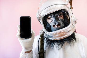Man with gorilla mask and astronaut helmet with a smart phone