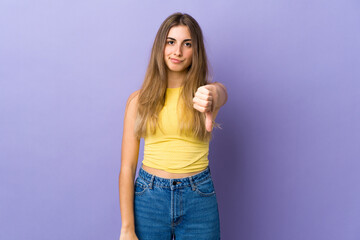 Young woman over isolated purple background showing thumb down with negative expression