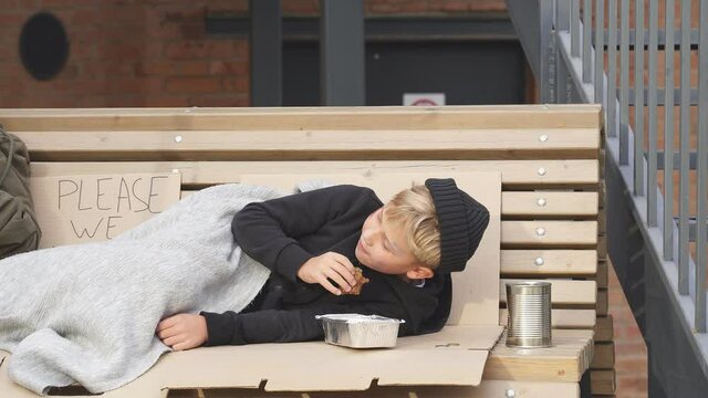 Poor homeless boy are hungry, asking help through the bars ,food donation from strangers, on street at big city, begging. Shelter concept.