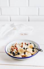Organic cottage cheese with date syrup and banana for healthy breakfast. White wooden table