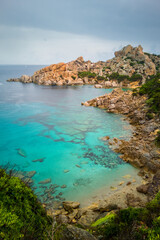 Clear sea water in bay at Capo Testa, Sardinia, Italy. Vivid blue/cyan water in shallow cove and eroded rock formation.