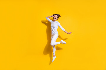 Fototapeta na wymiar Full length photo of pretty funny young woman wear white shirt jumping showing v-signs cover eye isolated yellow color background