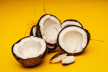 Parts of coconut on a colored background. Close up. Fresh ripe coconut broken into pieces.