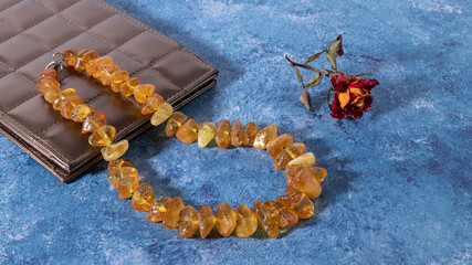 Fototapeta premium Beautiful sparkling transparent yellow amber necklace on a blue surface. Retro composition. 