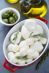 Serving pan with mozzarella cheese, giant green olives, rosemary and olive oil, vertical shot, selective focus
