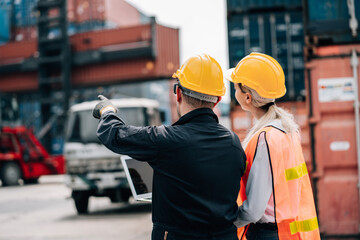 workers teamwork man and woman in safety jumpsuit workwear with yellow hardhat and use laptop check container at cargo shipping warehouse. transportation import,export logistic industrial service