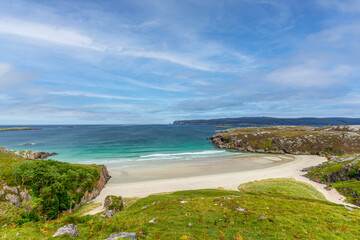 A scenics beautiful view of the Ceannabeinne Beach along the A838 touristic road near Durness in the Scottish Highland under a majestic blue sky and some white clouds.