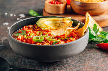 Chili Con Carne in bowl with tortilla chips on dark background. Mexican cuisine.
