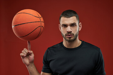 Young sportsman in black sportswear in cation on red background