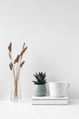 Mug and transparent vase with flowers on a white background. Eco-friendly materials in the decor of the room, minimalism. Copy space, mock up