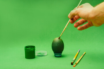 Man hand paints Easter egg with brush