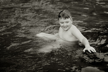 Black and white image of boy swimming in natural swimming hole in central New South Wales, Australia