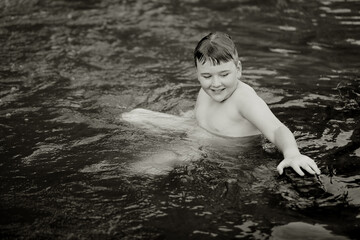 Fototapeta premium Black and white image of boy swimming in natural swimming hole in central New South Wales, Australia
