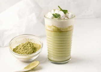 Matcha latte on a white plate with cream and marshmallows.