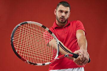 Handsome muscular athlete male in red shirt holding racket in tennis club