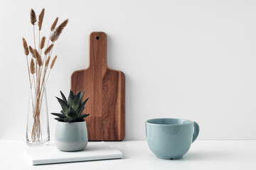 A mug and potted houseplant, a stack of books, a transparent vase and a wooden board. Eco-friendly materials in interior decor, minimalism. Copy space, mock up.