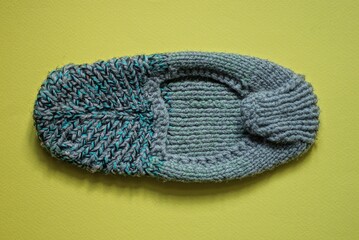 one gray green knitted woolen slipper stand on a yellow table