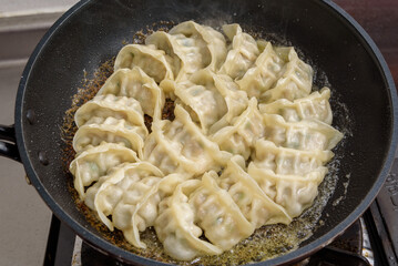 Baked dumplings being cooked in a frying pan