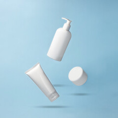 White jar and bottles for cosmetics products flying on blue background. Levitation. Body care...