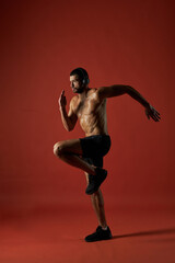 Fototapeta na wymiar Focused athlete man in headphones doing fitness exercises isolated on red background