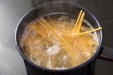 Spaghetti pasta boiling in cooking pan on stove.