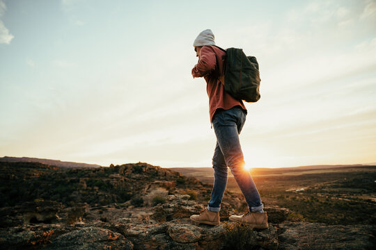 Caucasian male free spirit walking through wilderness at sunrise with backpack