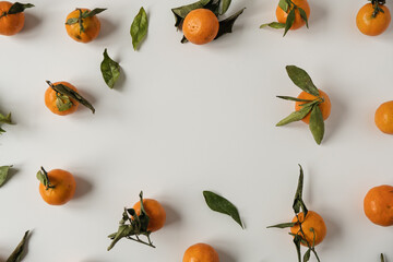 Frame with copy space. Oranges, tangerines with leaves pattern. Fresh healthy fruits, food background. Flatlay, top view.