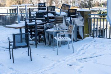 Fototapeta na wymiar Gestapelte Stühle mit Schnee bedeckt