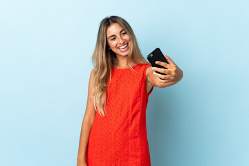 Fototapeta premium Young hispanic woman over isolated blue background making a selfie