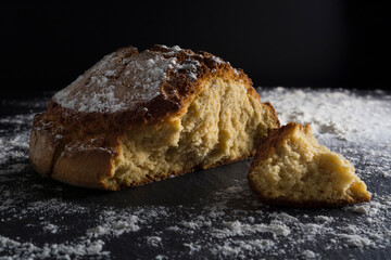 Pan de maíz abierto sobre fondo negro con harina