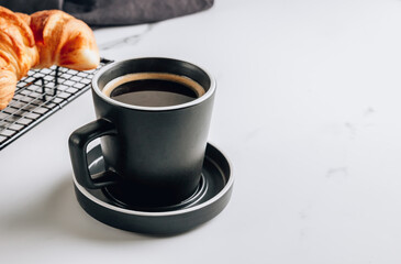 Croissants on cooling rack and cup of coffee.