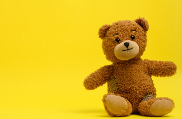 brown teddy bear sits on a yellow background