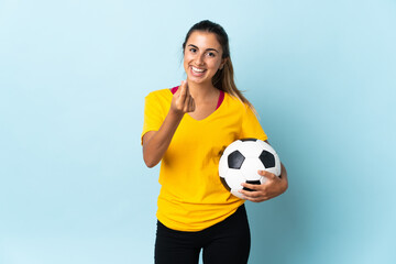 Young hispanic football player woman over isolated on blue background making money gesture