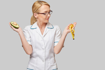 nutritionist doctor healthy lifestyle concept - holding organic avocado fruit and measure tape