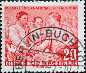 GERMANY, DDR - CIRCA 1955 : a postage stamp from Germany, GDR showing three women of different skin color, demonstration. International Women's Day