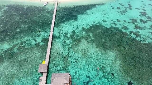 Top down view of pier and tilt up to reveal paradise Kanawa Island resort, Labuan Bajo, Indonesia