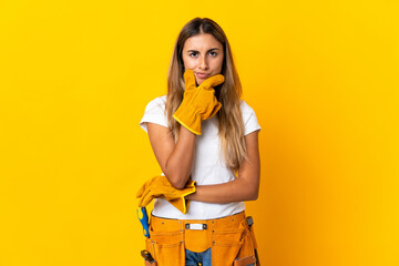Young hispanic electrician woman over isolated yellow wall thinking