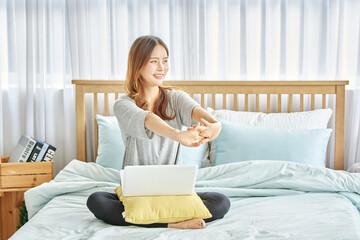 동양인 한국인 여성 모델 침대 위에서 노트북을 보며 스트레칭 