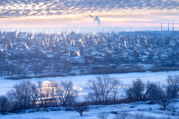 .Winter city landscape. Frosty sunny morning in the city, frozen river, people heat stoves, smoke in a pillar in the backlight