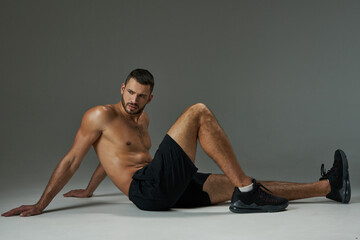Obraz premium Handsome adult Caucasian sportsman in sportswear relaxing after training isolated on grey background