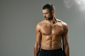 Fototapeta premium Focused adorable man with powerful torso standing in room indoors