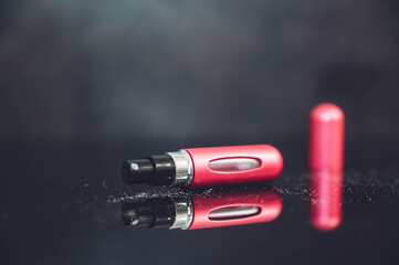 Perfume refillable aluminum atomizer isolated on black mirror background. Pink spray case for...